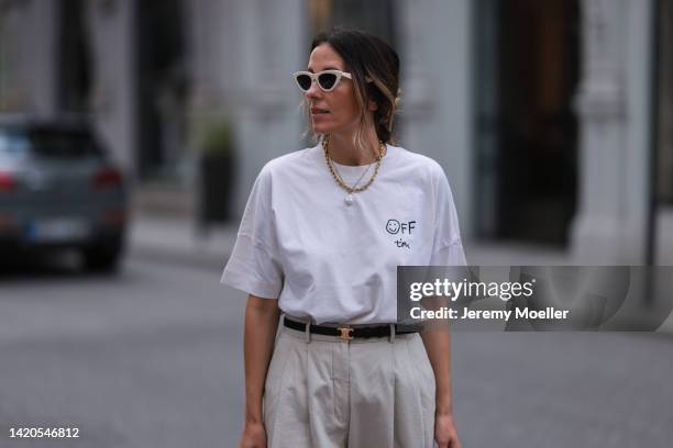 Elise Seitz seen wearing white Celine sunglasses, white logo t-shirt from Soho Studios, gold necklaces, creme beige Soho Studios wide leg suit pants,...