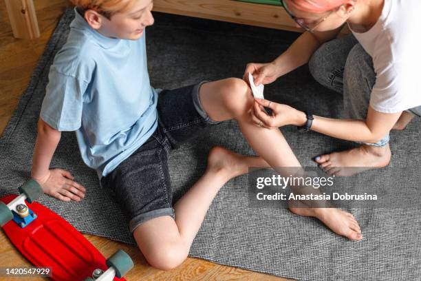 mother putting band aid on child's knee - applying plaster stock pictures, royalty-free photos & images