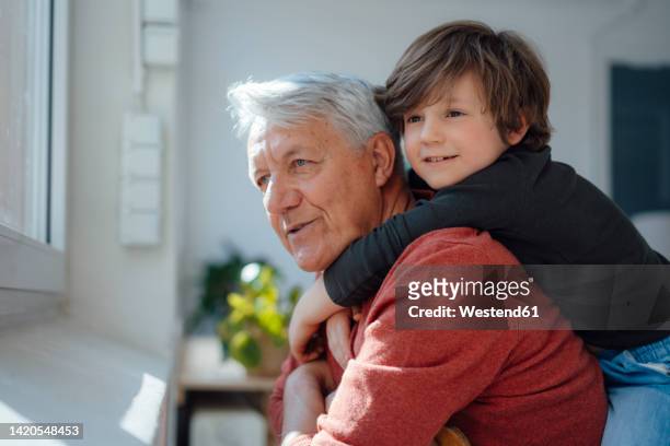 contemplative grandfather and grandson at home - enkelkind stock-fotos und bilder