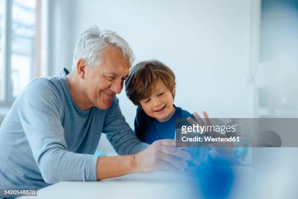 smiling senior man and grandson examining heating module at home - fuel and power generation stock-fotos und bilder