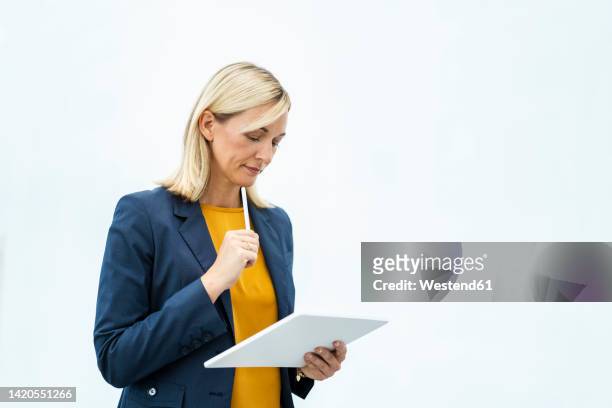 thoughtful businesswoman using tablet pc standing against white background - tablet freisteller stock-fotos und bilder