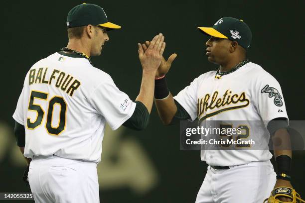 Grant Balfour of the Oakland Athletics celebrates victory with team mate Yoenis Cespedes during the MLB Opening Series game two between the Seattle...
