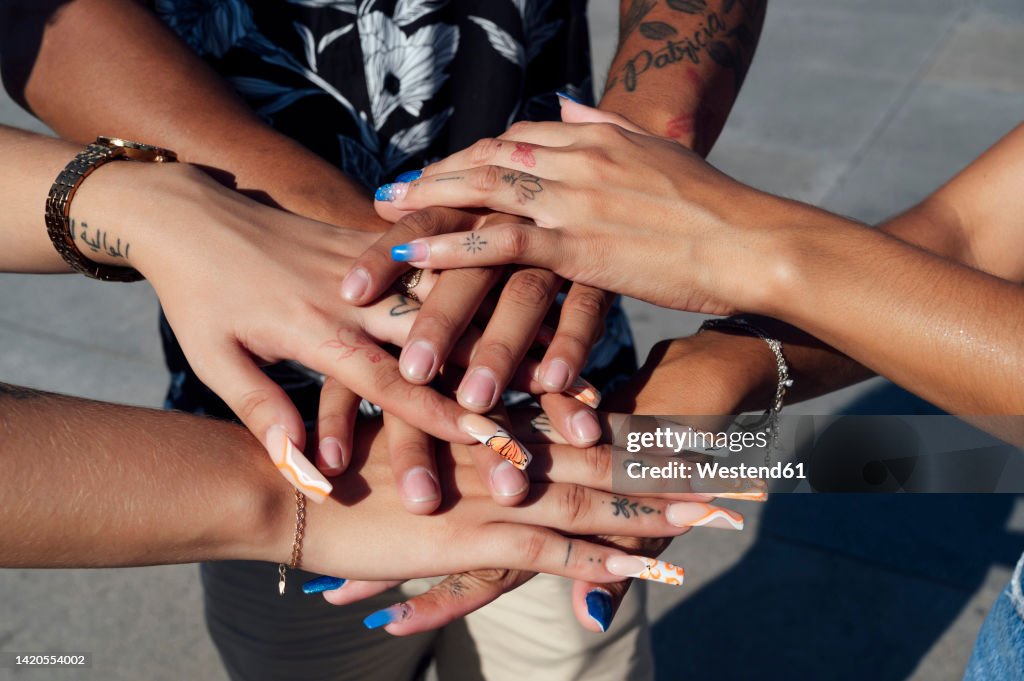 Hand's of friends stacked together on sunny day