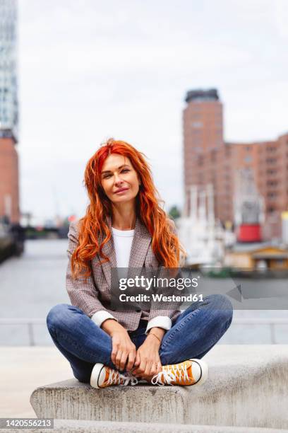 happy redhead woman sitting on bench at hafencity - concert hall exterior stock pictures, royalty-free photos & images