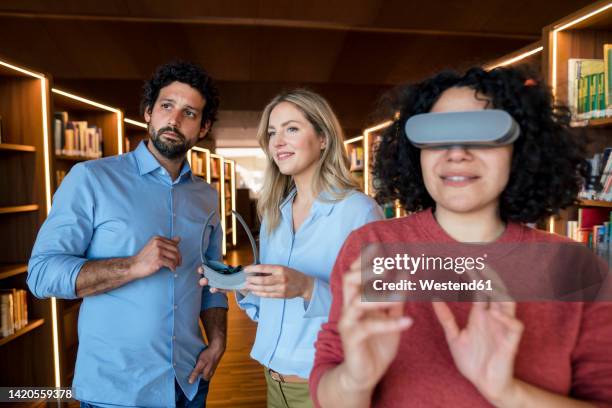 multiracial colleagues with vr glasses in illuminated library - virtual library stock pictures, royalty-free photos & images