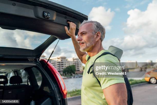 mature man with gray hair closing car trunk - closing car boot fotografías e imágenes de stock