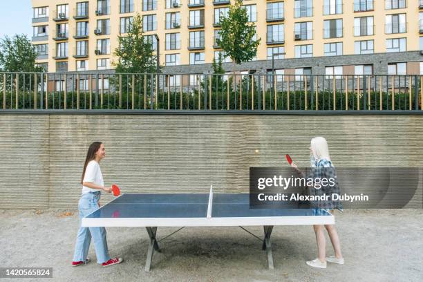 two girls play table tennis outdoors in summer - table tennis stock pictures, royalty-free photos & images