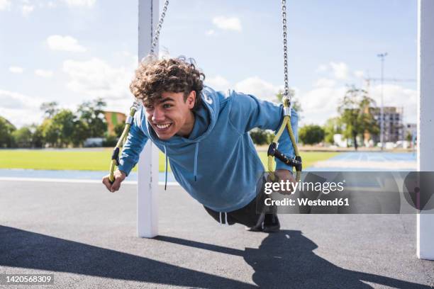 happy sportsman exercising with suspension straps at sport court - bodyweight training stock pictures, royalty-free photos & images