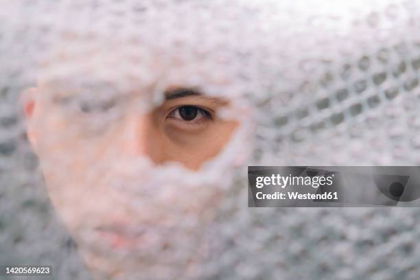 man looking through hole of bubble wrap paper - man wrapped in plastic stock pictures, royalty-free photos & images