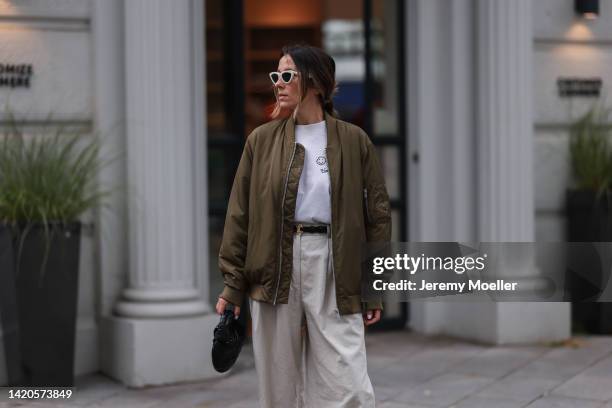 Elise Seitz seen wearing white Celine sunglasses, white logo t-shirt from Soho Studios, creme beige Soho Studios wide leg suit pants, khaki green...