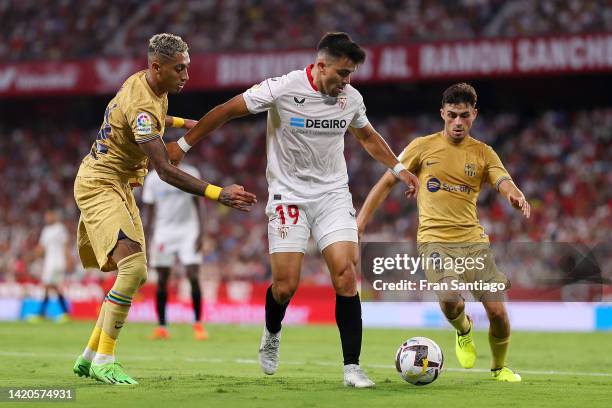 Marcos Acuna of Sevilla FC is marked by Raphinha and Pedri of FC Barcelona during the LaLiga Santander match between Sevilla FC and FC Barcelona at...