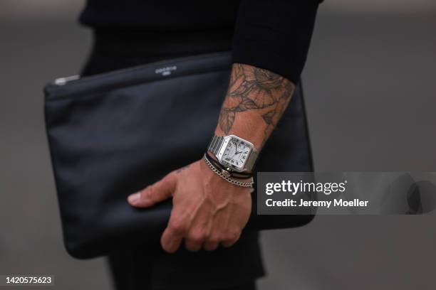 Andre Hellmundt wearing Sandro Paris shoes, Samsoe Samsoe trousers, Sandro clutch, Olymp navy blue sweater and a Cartier watch on August 31, 2022 in...