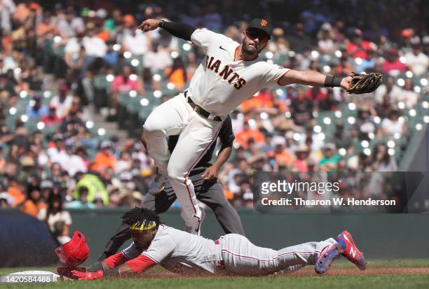 Jean Segura of the Philadelphia Phillies steals third base diving in under a leaping David Villar of the San Francisco Giants taking the throw in the...
