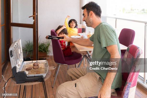 a table is set on the balcony of the house and meatballs are cooked on the barbecue. father prepares the dinner table. - broiling stock pictures, royalty-free photos & images