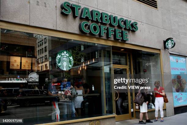 Two women chat in front of a Starbucks on September 3, 2022 in New York City. The Department of Consumer and Worker Protection has sued Starbucks for...