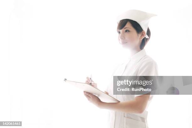 young nurse holding clipboard - nurse hat stock pictures, royalty-free photos & images