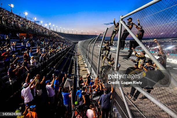 Noah Gragson, driver of the Bass Pro Shops/TrueTimber/BRCC Chevrolet, and crew celebrate by climbing the fence to celebrate with fans after winning...