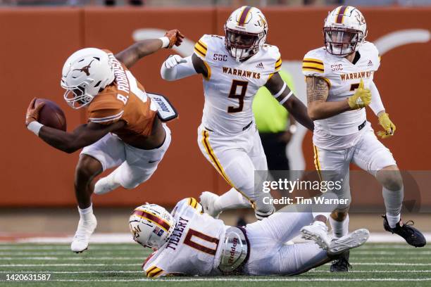 Bijan Robinson of the Texas Longhorns is tripped up by Lu Tillery of the Louisiana Monroe Warhawks in the first half at Darrell K Royal-Texas...