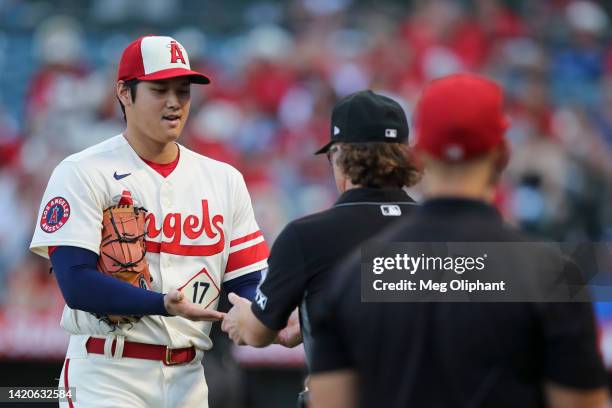 Shohei Ohtani of the Los Angeles Angels has his hands checked after pitching in the first inning by umpire Chris Guccione during the game against the...