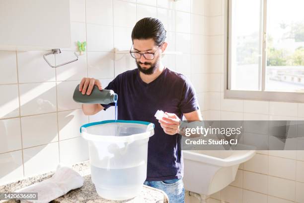 young latin man performing cleaning in empty apartment. - daily bucket stockfoto's en -beelden