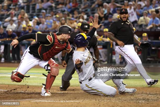 Jace Peterson of the Milwaukee Brewers safely slides into home plate to score a run past catcher Carson Kelly of the Arizona Diamondbacks during the...