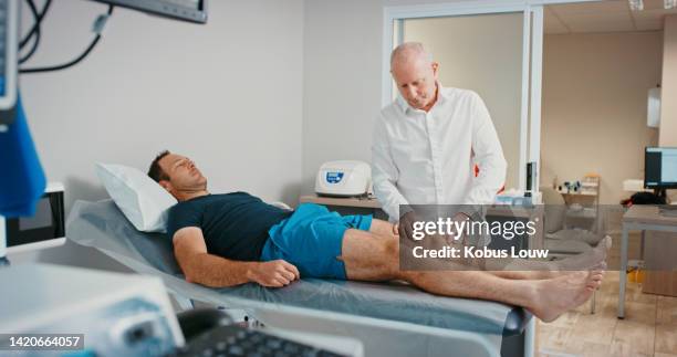 physiotherapist doctor with patient in physical therapy for legs or muscle pain in a hospital exam consultation. senior healthcare professional doing examination of of sports man on orthopedic table - right knee anatomy stock pictures, royalty-free photos & images