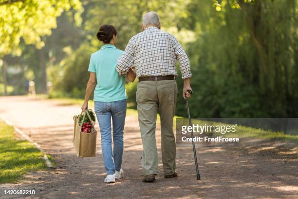 caregiver – woman helping senior man with shopping - home carer 個照片及圖片檔