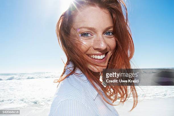 young woman smiling at beach - sun flare foto e immagini stock