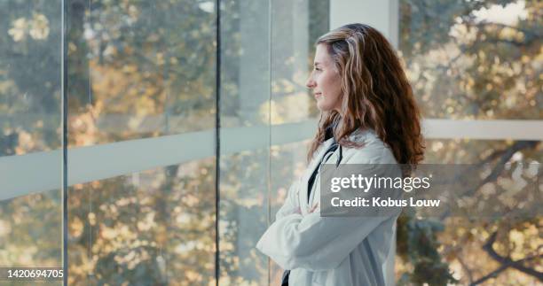 relax, thinking and happy work mindset looking out a window at nature with a young doctor. calm, content and serene woman medical and healthcare professional feeling job hope and career happiness - olhar através da janela imagens e fotografias de stock