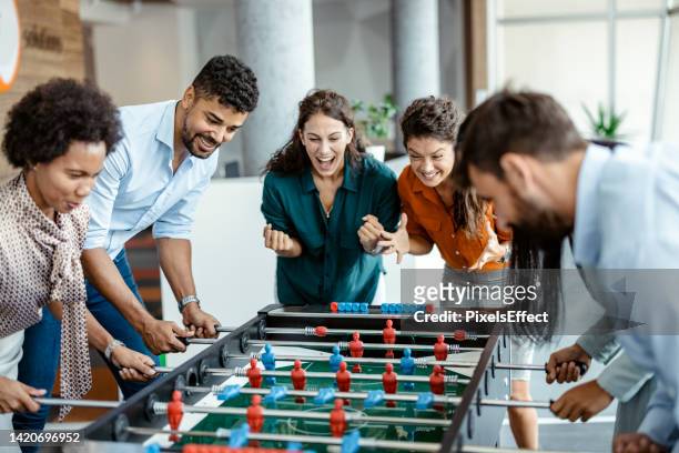 colleagues playing table football - employee wellbeing stock pictures, royalty-free photos & images