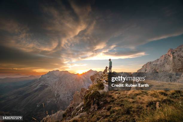 young sportswoman with her dog looking at the mountains of picos de europa at sunrise - runner sunrise stock pictures, royalty-free photos & images