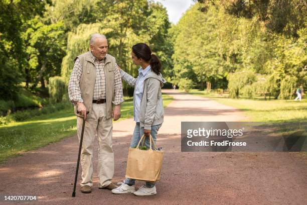 seniorenmann mit rollstuhl und betreuer - client carer stock-fotos und bilder