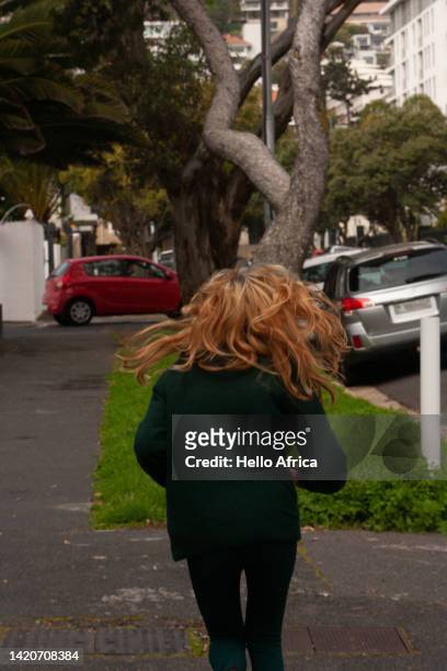 a shock of blond hair in movement seen from behind, the rear view of a running young woman with her hair wildly dancing in mid mid-air - vaulting gymnastics stock pictures, royalty-free photos & images