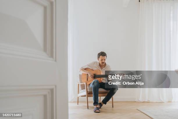 man playing guitar in the living room - music room stockfoto's en -beelden