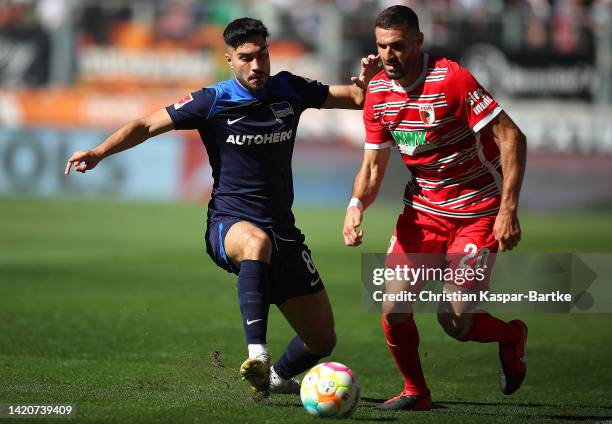 Daniel Caligiuri of Augsburg is challenged by Suat Serdar of Hertha Berlin during the Bundesliga match between FC Augsburg and Hertha BSC at...