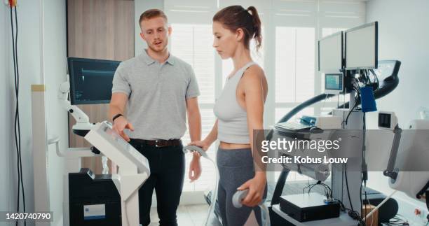 fitness test for a female high performance athlete in a health center or sports science lab to examine her cardio. coach or physiotherapist using technology to help a woman with physiotherapy - treadmill test stockfoto's en -beelden