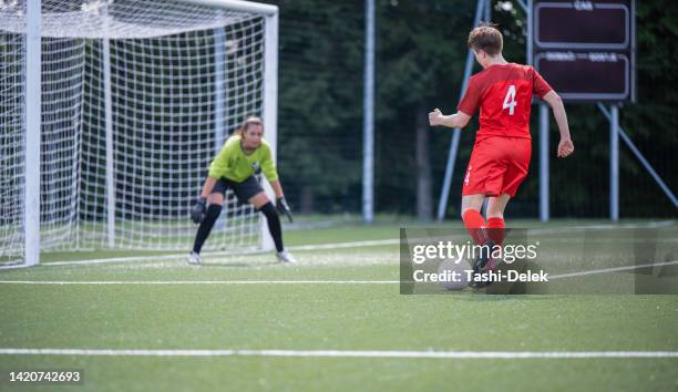 shot of determined female soccer player kicking the ball on  a match - girl kicking stock pictures, royalty-free photos & images