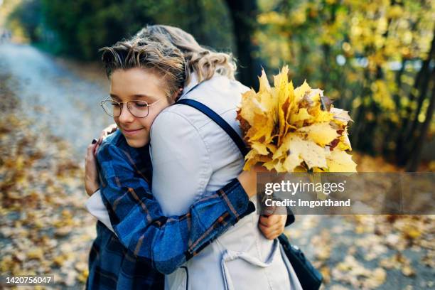 teenage boy with with bouquet of autumn leaves is hugging his mother. - 12 year old cute boys stock pictures, royalty-free photos & images