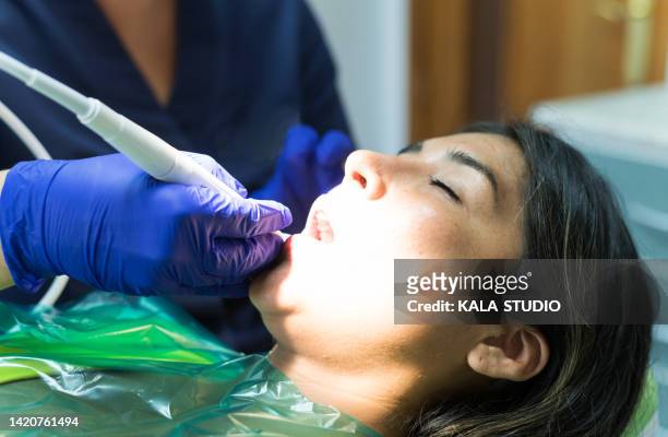 hands of a dentist performing a root canal on a lying patient. dentist performing a root canal on a female patient - デンタルダム ストックフォトと画像