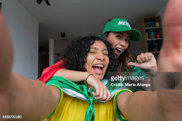 couple of friends from different countries dressed in their uniforms and flags taking a selfie - spectator selfie stock pictures, royalty-free photos & images