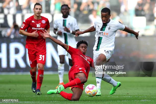 Alassane Plea of Borussia Monchengladbach is tackled by Leandro Barreiro of FSV Mainz during the Bundesliga match between Borussia Moenchengladbach...