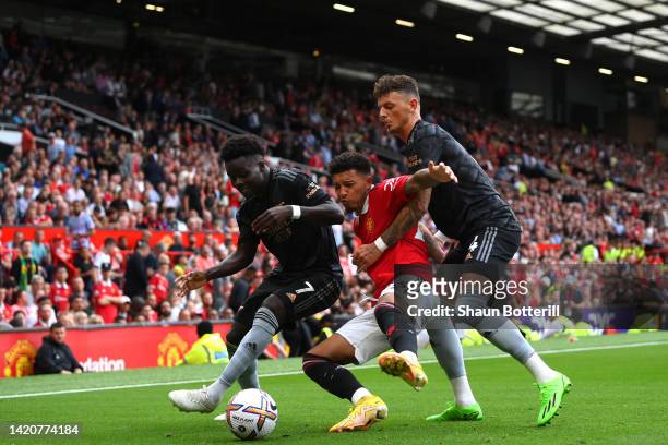 Jadon Sancho of Manchester United is tackled by Bukayo Saka and Ben White of Arsenal during the Premier League match between Manchester United and...