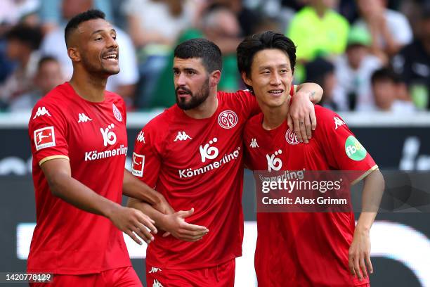Aaron Caricol of FSV Mainz celebrates with teammates Karim Onisiwo and Jae-sung Lee after scoring their team's first goal from a free kick during the...