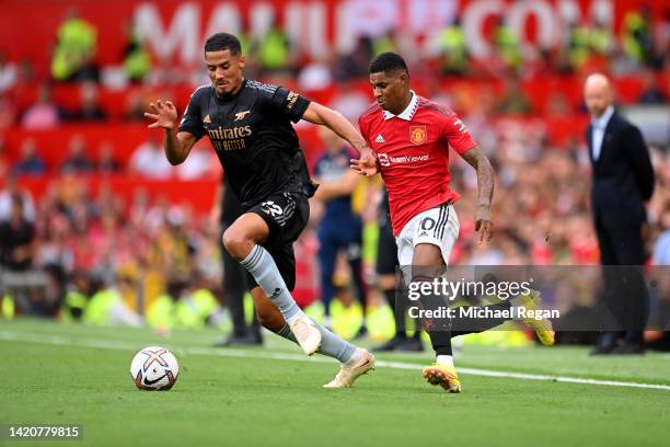 William Saliba of Arsenal is challenged by Marcus Rashford of Manchester United during the Premier League match between Manchester United and Arsenal...