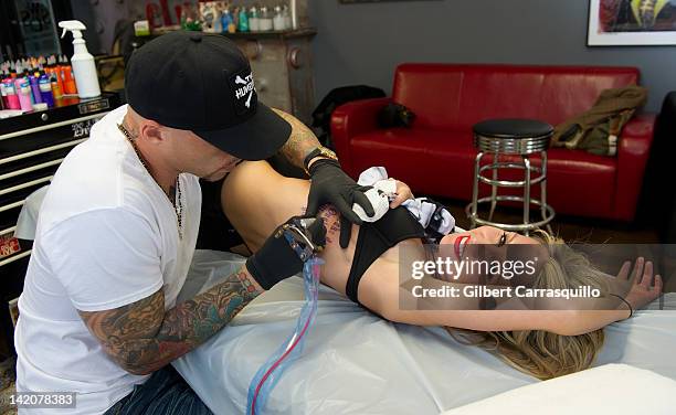 Lead singer Camilla Romestrand of the UK rock band Eddie The Gun gets tattooed by tattoo artist Ami James to promote the release of the new digital...