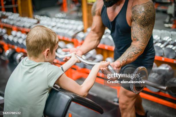 boy doing exercises in the gym with a man trainer athletic physique - young kid and barbell stock pictures, royalty-free photos & images