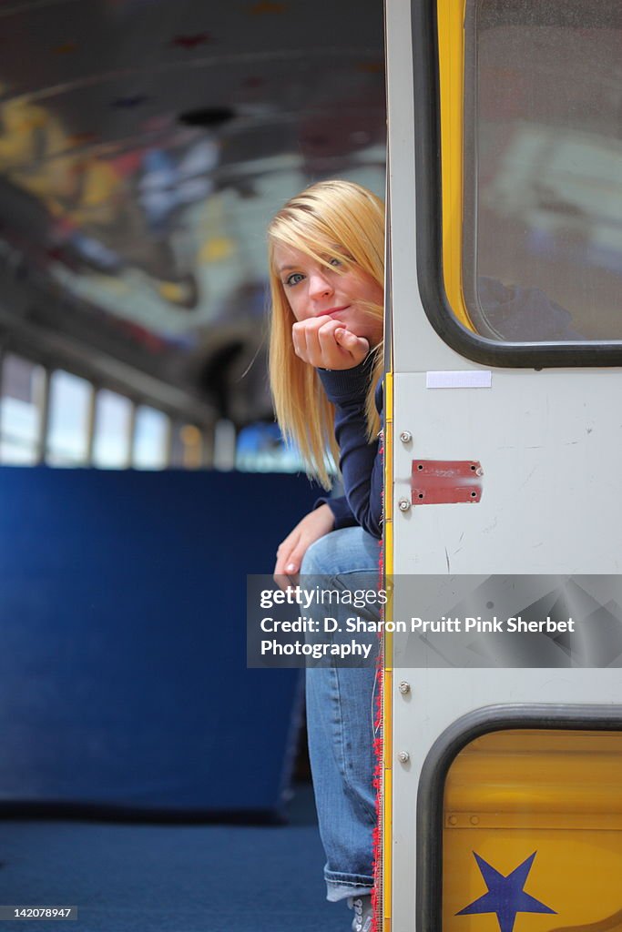 Teen girl peeking from school bus emergency exit