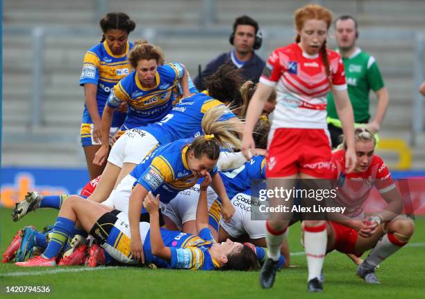 The players of Leeds Rhinos mob Zoe Hornby after she scored their third try during the Betfred Women's Super League Semi Final match between St...