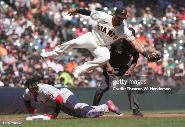 Jean Segura of the Philadelphia Phillies steals third base diving in under a leaping David Villar of the San Francisco Giants taking the throw in the...