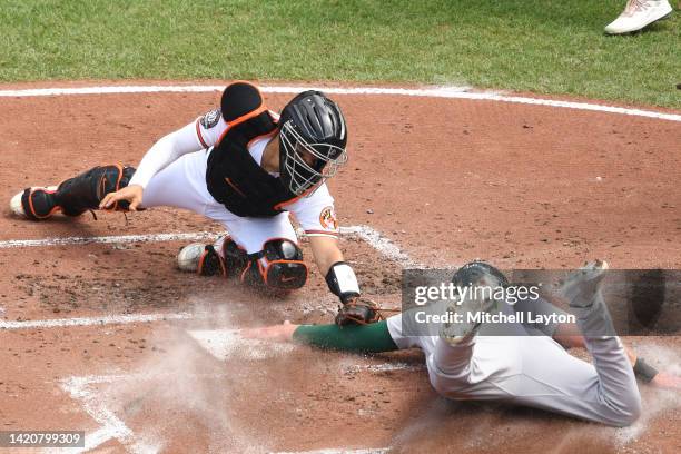 Seth Brown of the Oakland Athletics beats the tag by Robinson Chirinos of the Baltimore Orioles to score on a single off the bat of Sheldon Neuse in...